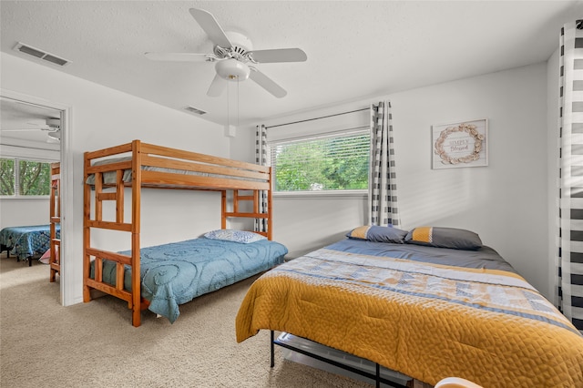 bedroom with carpet flooring, a textured ceiling, multiple windows, and ceiling fan