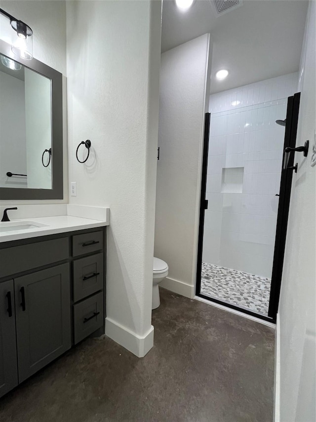 bathroom with a tile shower, vanity, concrete floors, and toilet