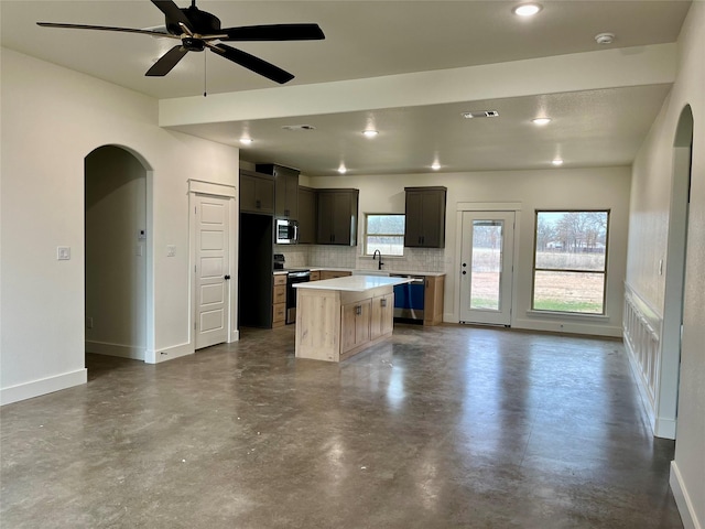 kitchen with sink, tasteful backsplash, appliances with stainless steel finishes, a kitchen island, and ceiling fan