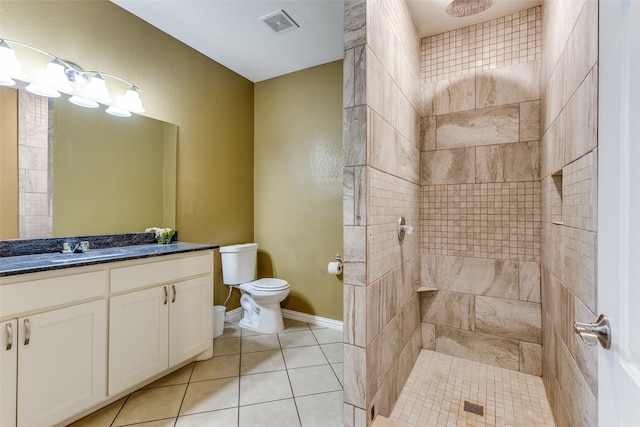 bathroom featuring vanity, toilet, tiled shower, and tile patterned floors