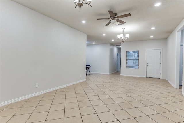 empty room featuring ceiling fan with notable chandelier and light tile patterned flooring