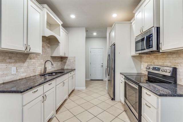 kitchen with stainless steel appliances, sink, decorative backsplash, white cabinetry, and dark stone counters