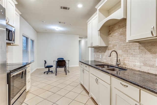 kitchen featuring backsplash, appliances with stainless steel finishes, sink, white cabinetry, and dark stone counters