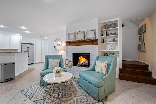 sitting room featuring a brick fireplace, stairway, and light tile patterned floors