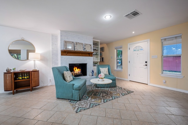 living room with a brick fireplace and light tile patterned flooring