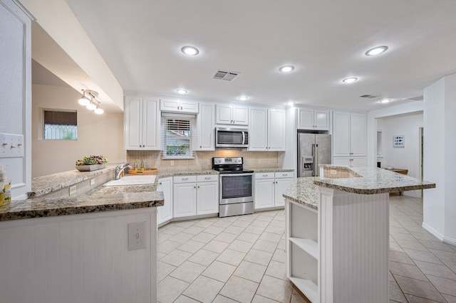 kitchen with sink, kitchen peninsula, a kitchen bar, white cabinetry, and stainless steel appliances