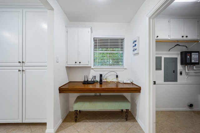 interior space with light tile patterned floors, cabinet space, electric panel, and baseboards