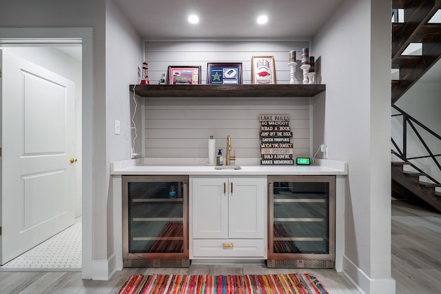 bar featuring light wood-type flooring, white cabinetry, sink, and wine cooler