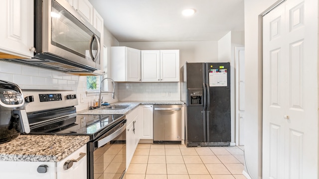 kitchen with white cabinetry, backsplash, stainless steel appliances, sink, and light tile patterned flooring