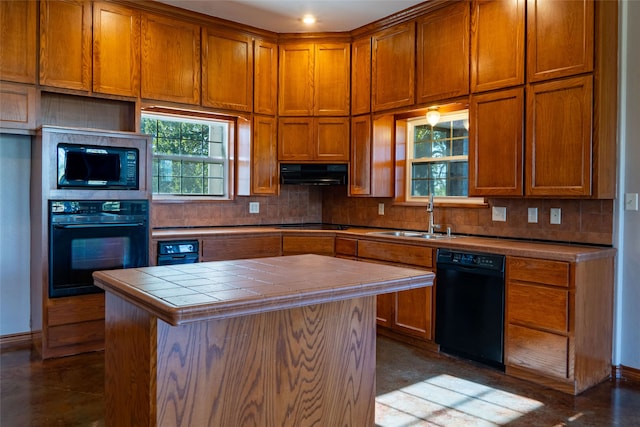 kitchen with tile counters, black appliances, exhaust hood, a kitchen island, and sink