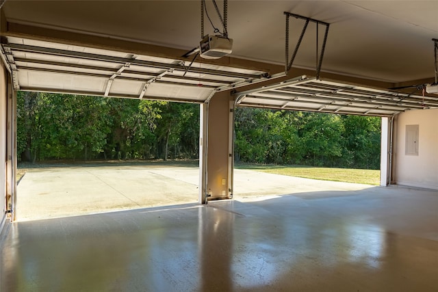 garage featuring electric panel, a garage door opener, and a carport