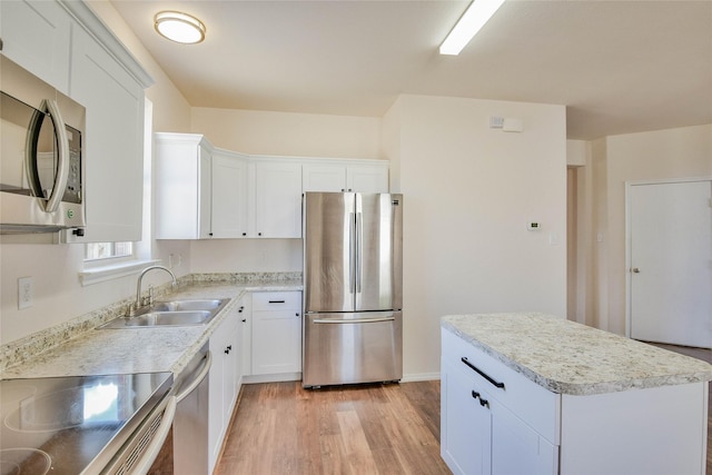 kitchen featuring a center island, sink, appliances with stainless steel finishes, white cabinets, and light wood-type flooring