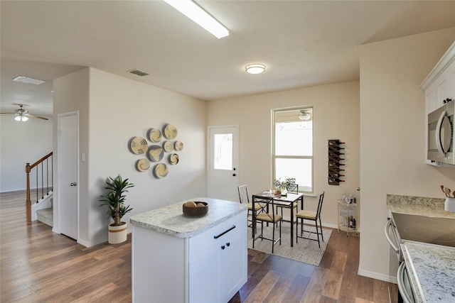 kitchen featuring white cabinets, a center island, stainless steel appliances, and dark wood-type flooring