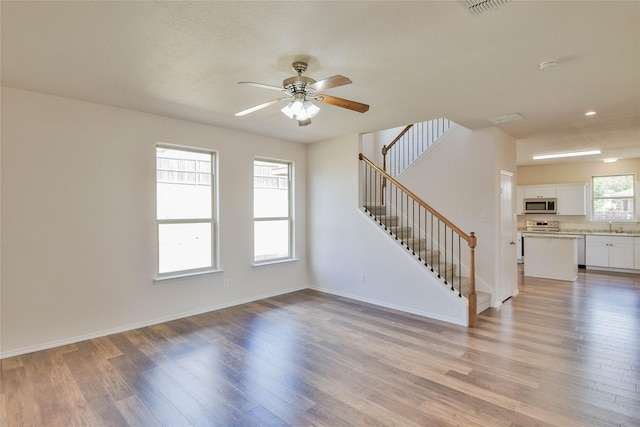 unfurnished living room featuring a textured ceiling, light hardwood / wood-style flooring, ceiling fan, and sink