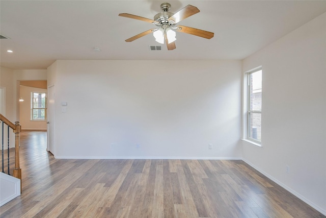 empty room with hardwood / wood-style floors, plenty of natural light, and ceiling fan