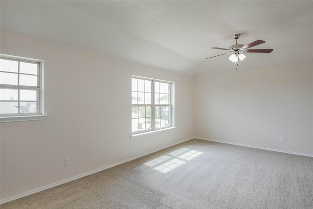 carpeted spare room with plenty of natural light, lofted ceiling, and ceiling fan