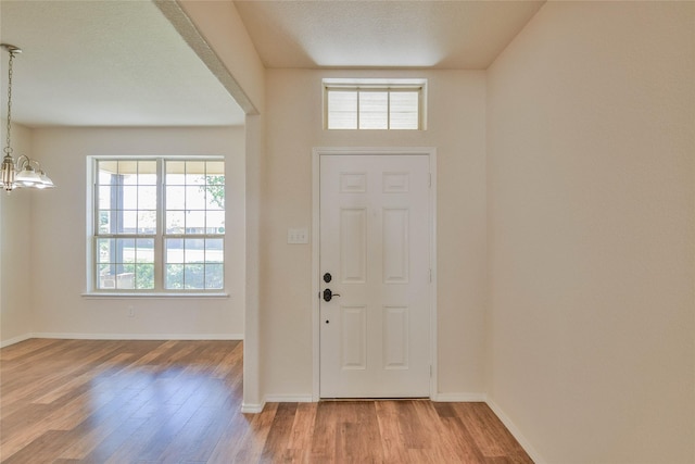 foyer entrance featuring a chandelier, wood-type flooring, and a textured ceiling