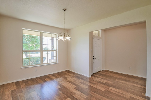 unfurnished room featuring a notable chandelier and dark hardwood / wood-style flooring