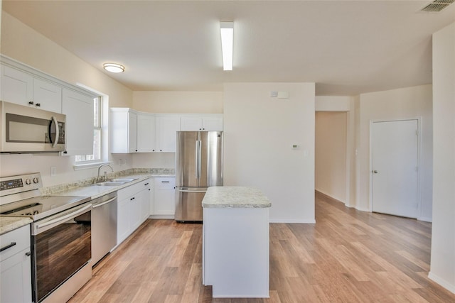 kitchen featuring white cabinets, a kitchen island, light wood-type flooring, and appliances with stainless steel finishes