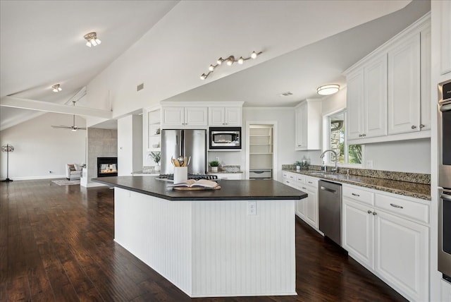 kitchen with a kitchen island, stainless steel appliances, white cabinets, and a tile fireplace