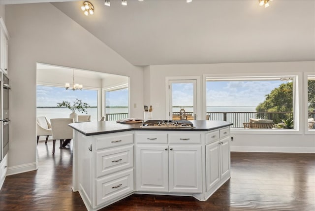 kitchen with stainless steel gas stovetop, a center island, an inviting chandelier, dark hardwood / wood-style floors, and pendant lighting