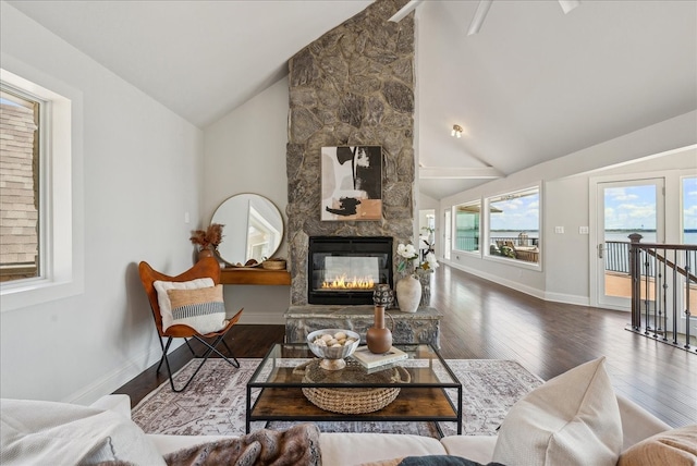 living room featuring high vaulted ceiling, hardwood / wood-style flooring, and a stone fireplace