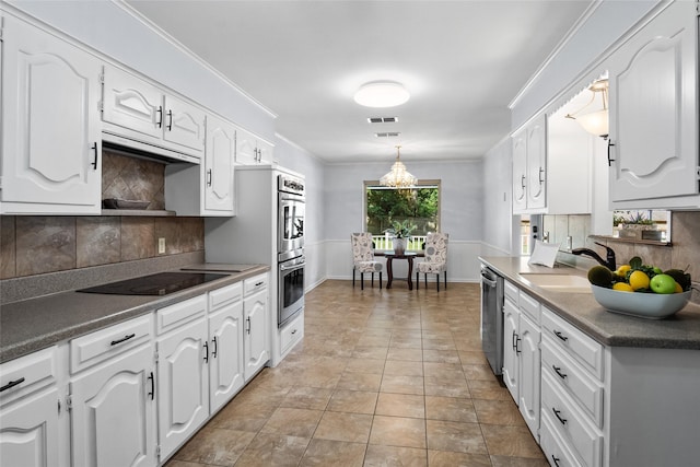 kitchen with white cabinets, appliances with stainless steel finishes, crown molding, and a sink