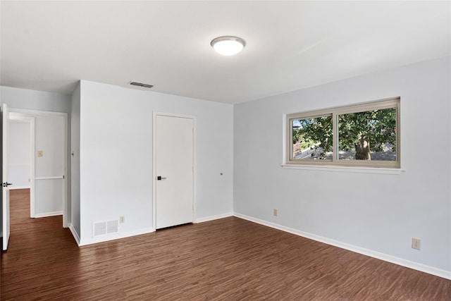 unfurnished bedroom featuring visible vents, baseboards, and dark wood-style flooring