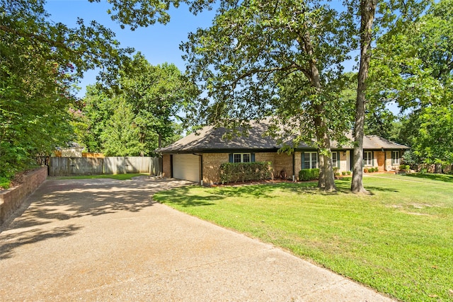 ranch-style house with fence, concrete driveway, a front yard, an attached garage, and brick siding