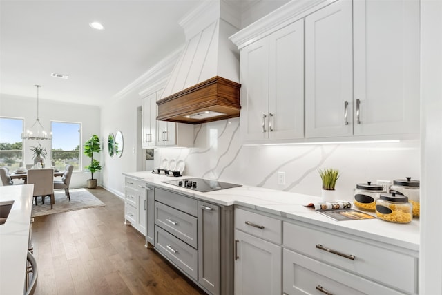 kitchen with an inviting chandelier, light stone counters, custom exhaust hood, dark hardwood / wood-style flooring, and black electric stovetop