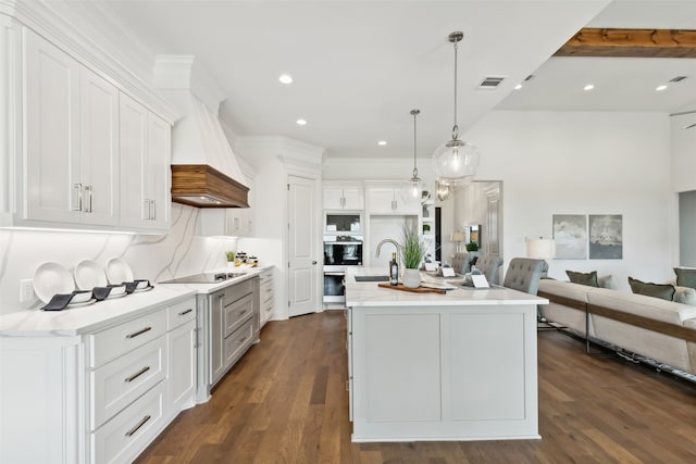 kitchen featuring dark hardwood / wood-style flooring, black appliances, a kitchen island with sink, hanging light fixtures, and sink