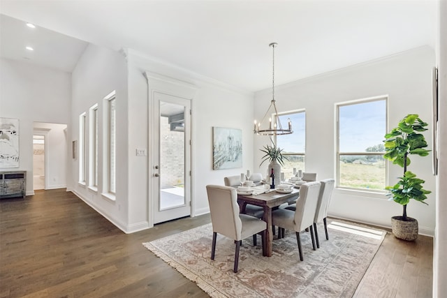 dining space with dark wood-type flooring, an inviting chandelier, and ornamental molding