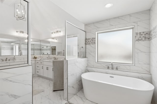 bathroom with vanity, tile walls, an inviting chandelier, and a bathtub