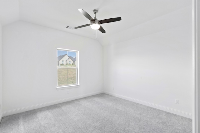 carpeted spare room featuring vaulted ceiling and ceiling fan