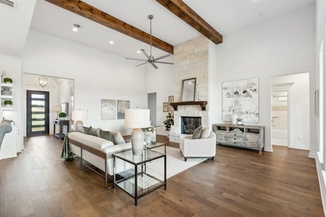 living room featuring a towering ceiling, dark hardwood / wood-style flooring, ceiling fan, and a stone fireplace