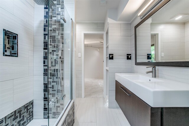 bathroom with tiled shower, vanity, tile patterned floors, and tile walls