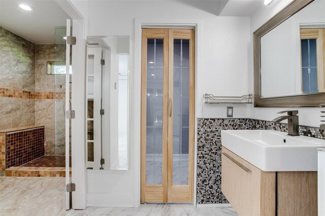 full bath with a tile shower, vanity, tile patterned floors, and tile walls