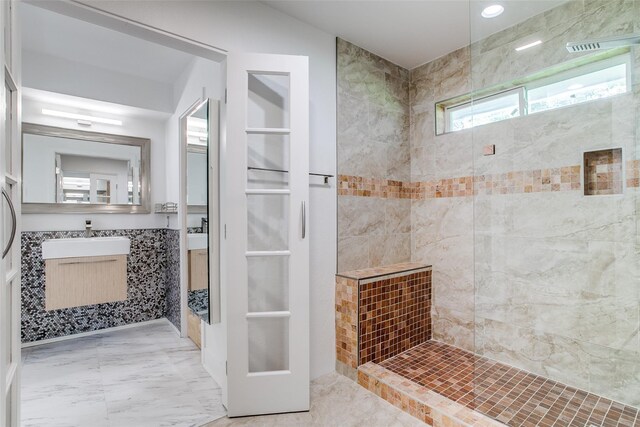 full bathroom with a shower stall, marble finish floors, vanity, recessed lighting, and tile walls
