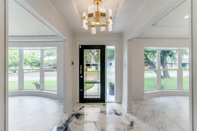 foyer entrance with a chandelier, marble finish flooring, baseboards, and crown molding