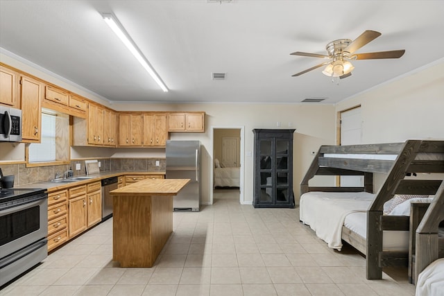 kitchen featuring stainless steel appliances, sink, a center island, light tile patterned flooring, and ceiling fan