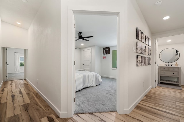 hall with vaulted ceiling and light hardwood / wood-style flooring