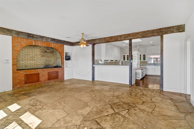 interior space featuring tile patterned flooring, brick wall, ceiling fan, and beam ceiling