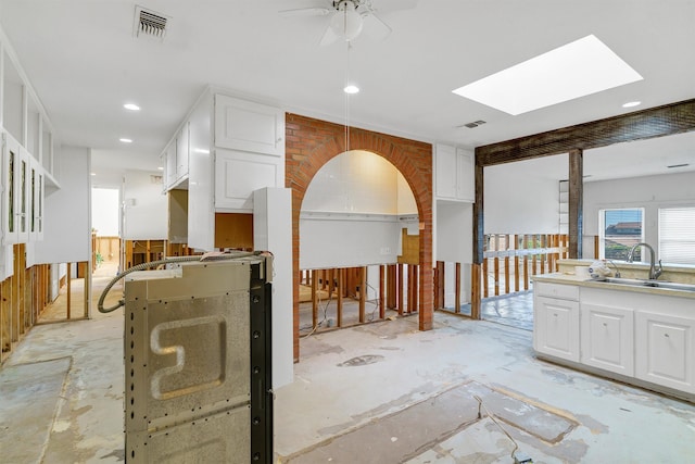 interior space featuring ceiling fan, sink, and a skylight