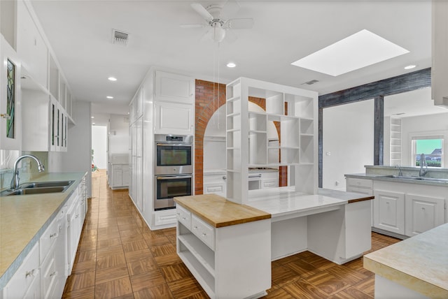 kitchen featuring light parquet floors, a kitchen island, sink, and white cabinets