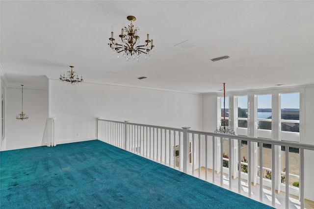 empty room with a water view, ornamental molding, carpet floors, and a chandelier