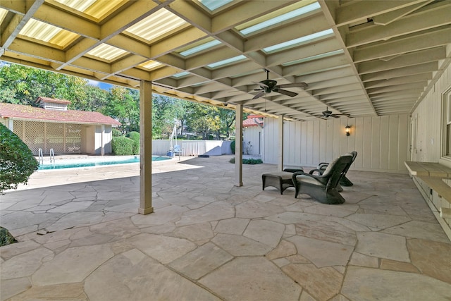 view of patio / terrace featuring ceiling fan, an outdoor structure, and a fenced in pool