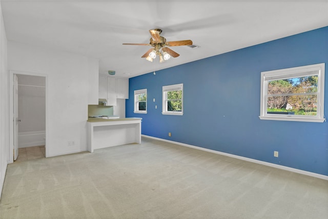 unfurnished living room featuring ceiling fan and light carpet