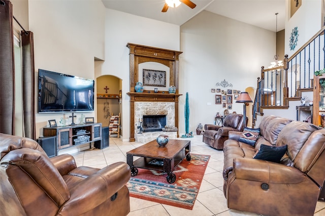 tiled living room with a stone fireplace, high vaulted ceiling, and ceiling fan