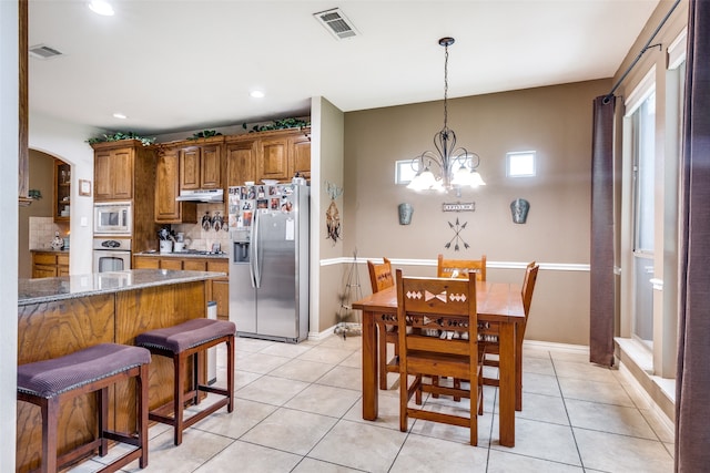 kitchen with stainless steel appliances, dark stone counters, pendant lighting, decorative backsplash, and a chandelier