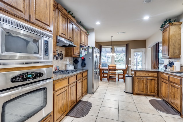 kitchen featuring decorative backsplash, stainless steel appliances, light stone counters, and light tile patterned floors